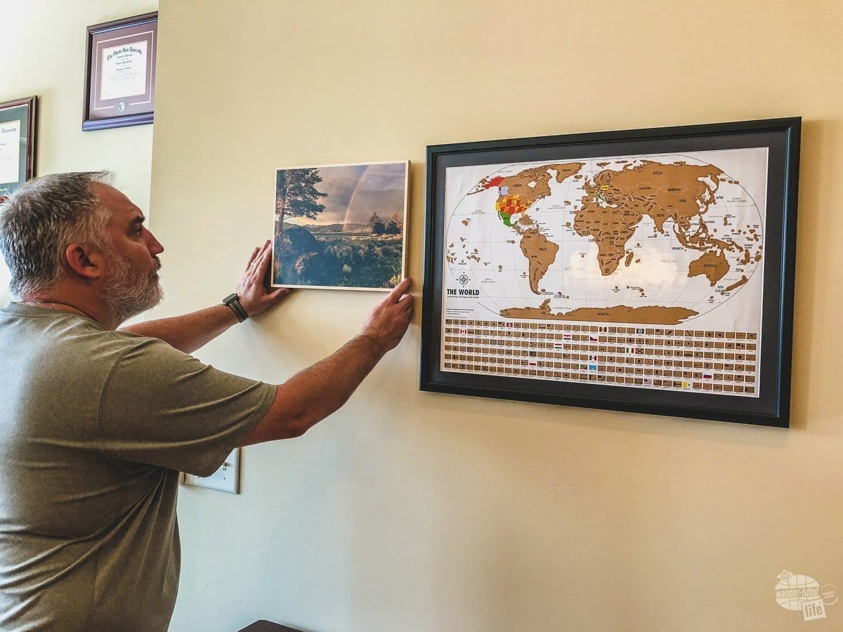 So, we got the Landmass Goods Travel Tracker Scratch Off map hung and now we are hanging one picture from every trip surrounding the map.