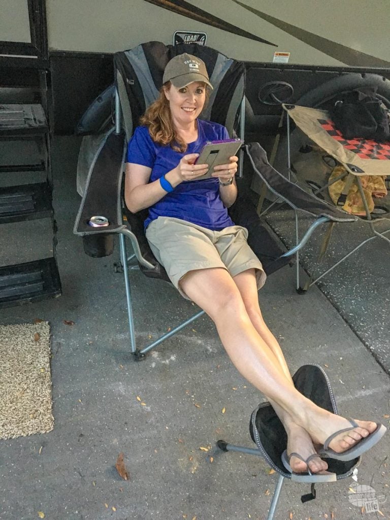 Bonnie reading a book on her iPad at the camper.