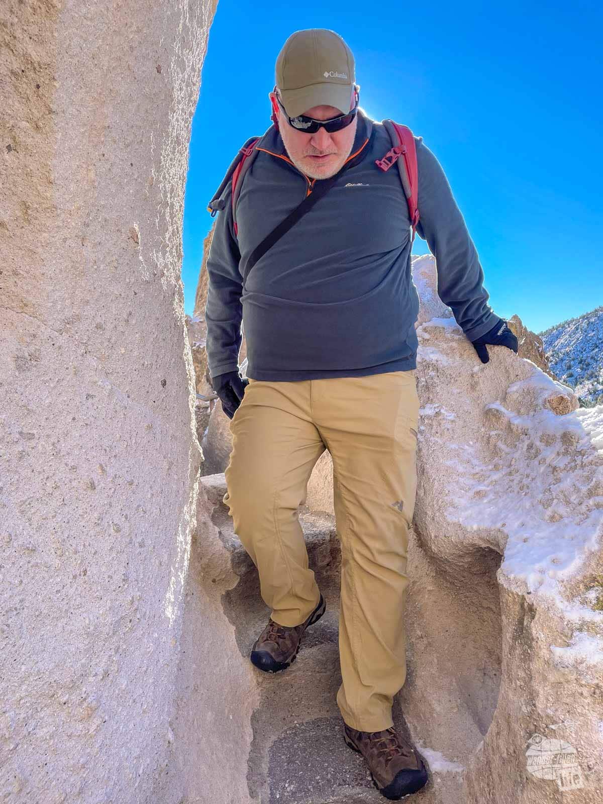 Grant carefully walks down a narrow staircase in the rock.