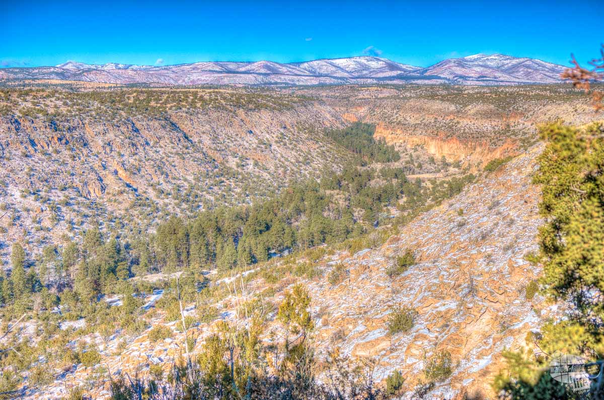 A shallow canyon with mountains in the distance at Bandelier National Monument.