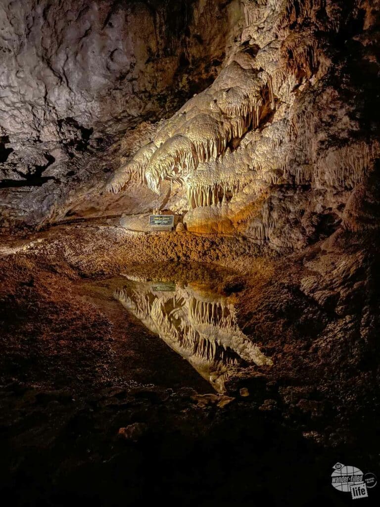 A small underground lake provides a reflection of the cave.