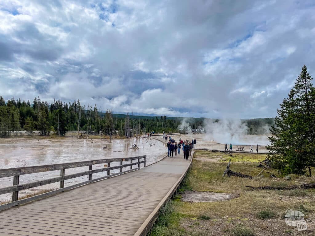Visitors walk along a boardwalk viewing thermal features.