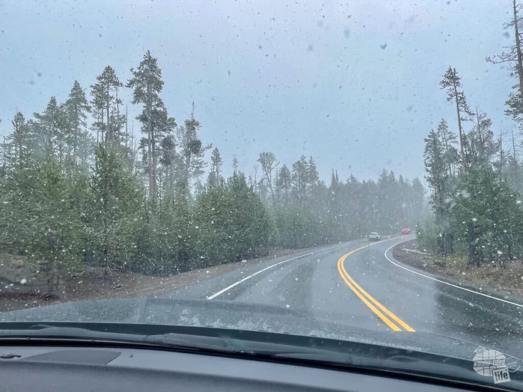 Snow falls while driving on a two-lane road.