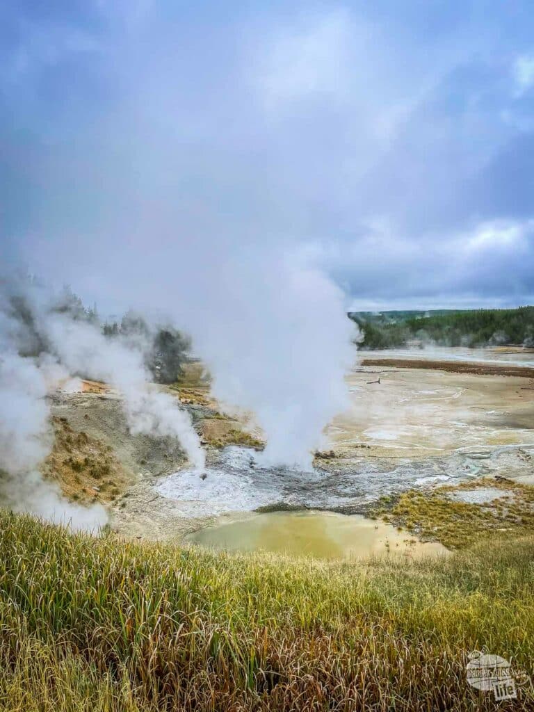 Steam rises from several thermal features. 