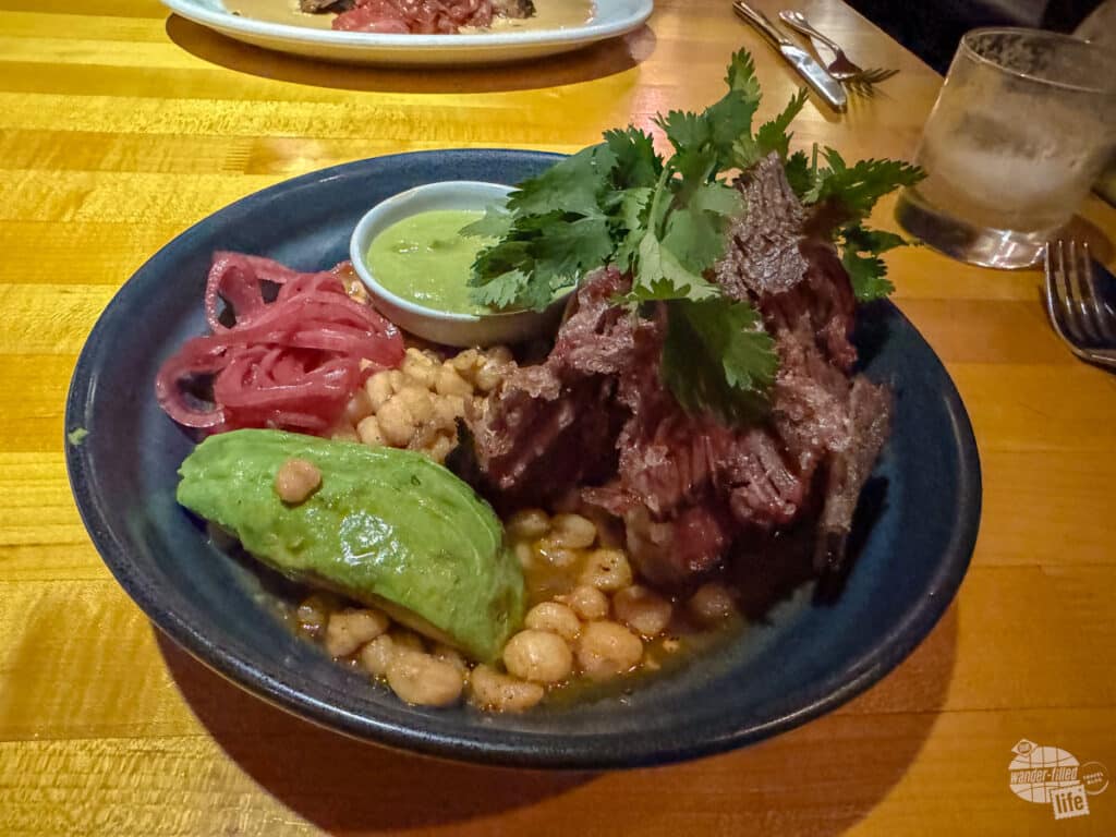 A bowl filled with beans, roasted pork, red onion, and avocado at a restaurant in Austin.