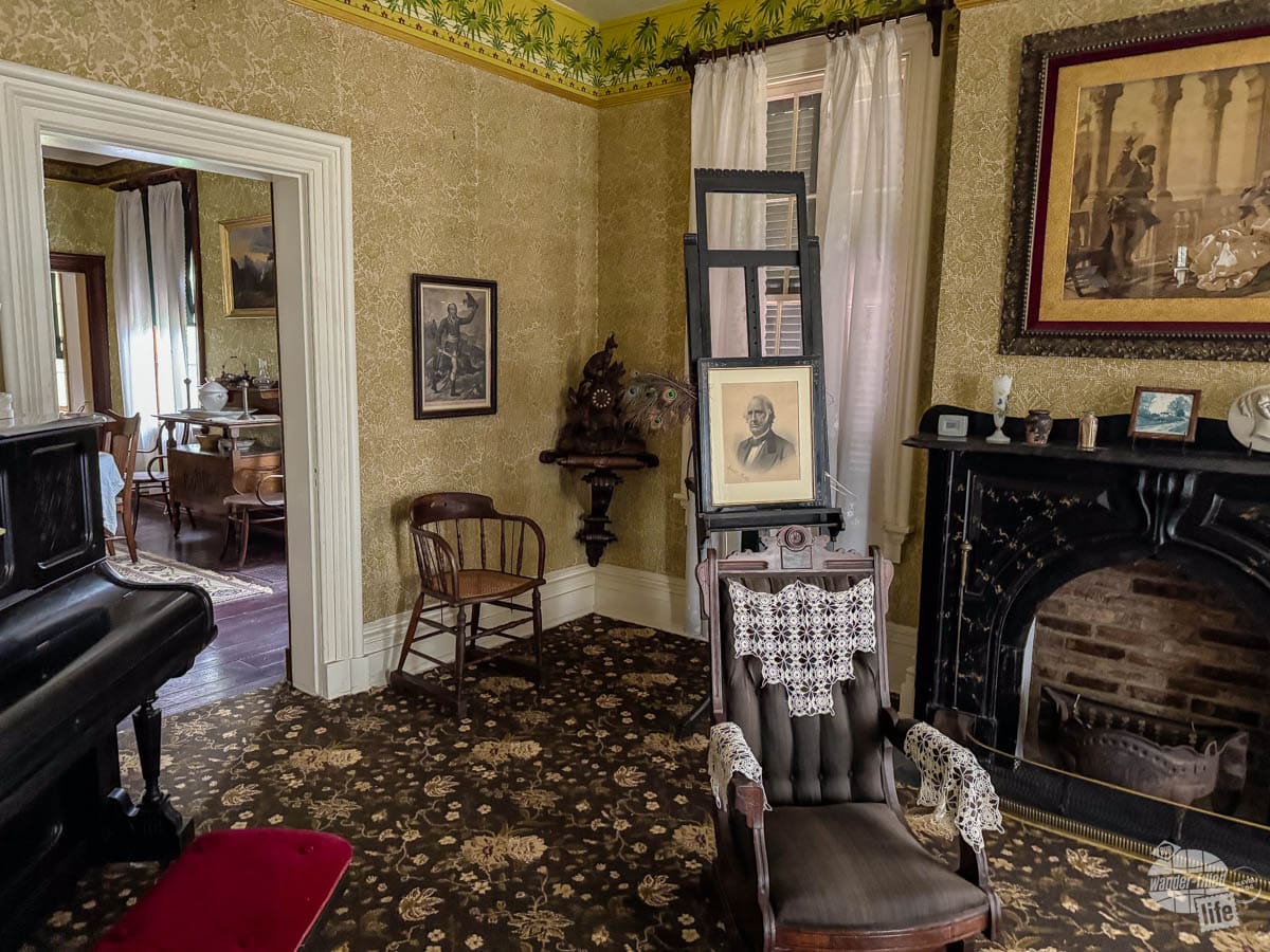 Inside the Frederick Douglass National Historic Site in Washington, DC. Photo shows a living room with fireplace, chair and piano.