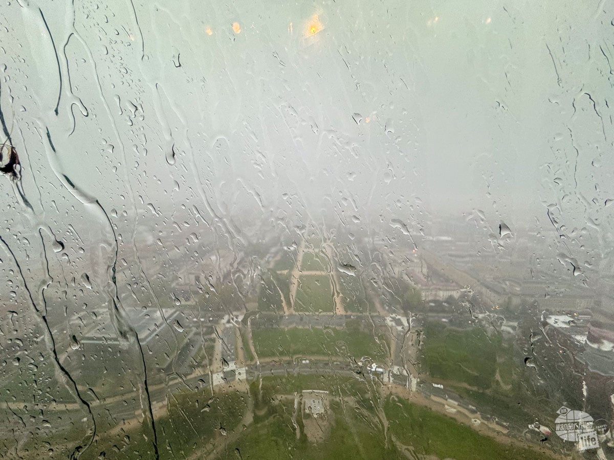 The view from the Washington Monument on a rainy day. The window is streaked with water and you can barely see the ground below.