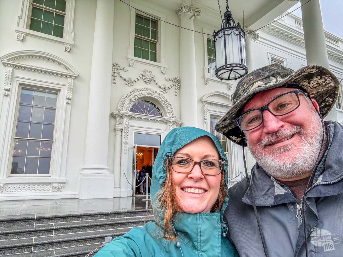 Grant and Bonnie in rain gear taking a selfie in front of the White House.