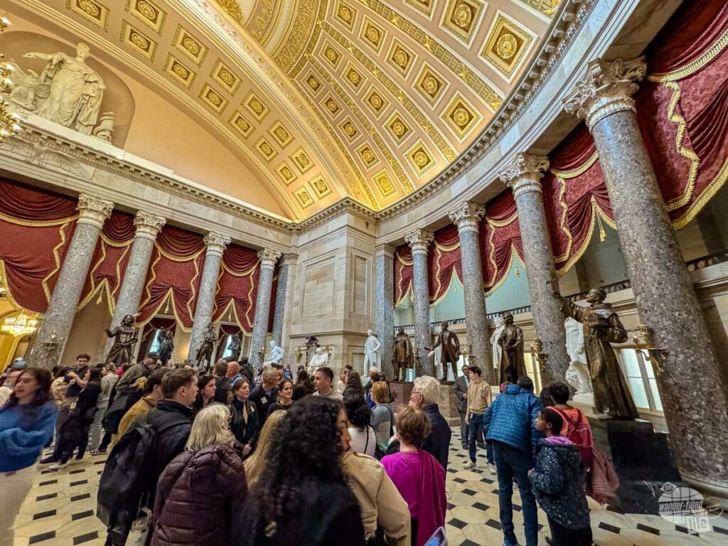 A group of people inside a hall of statues.