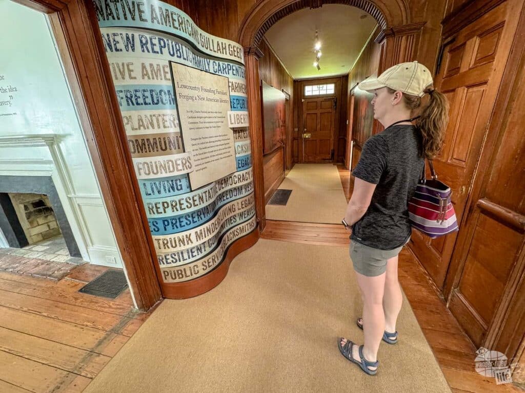 A woman standing the foyer of a home looking at an exhibit.