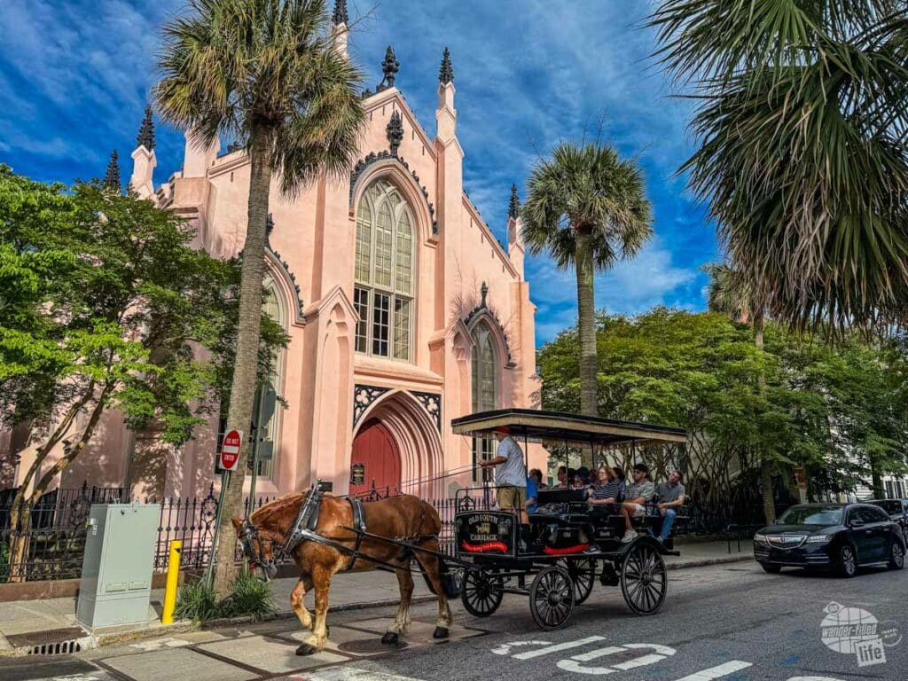 A horse-drawn carriage with tourists in front of a church.