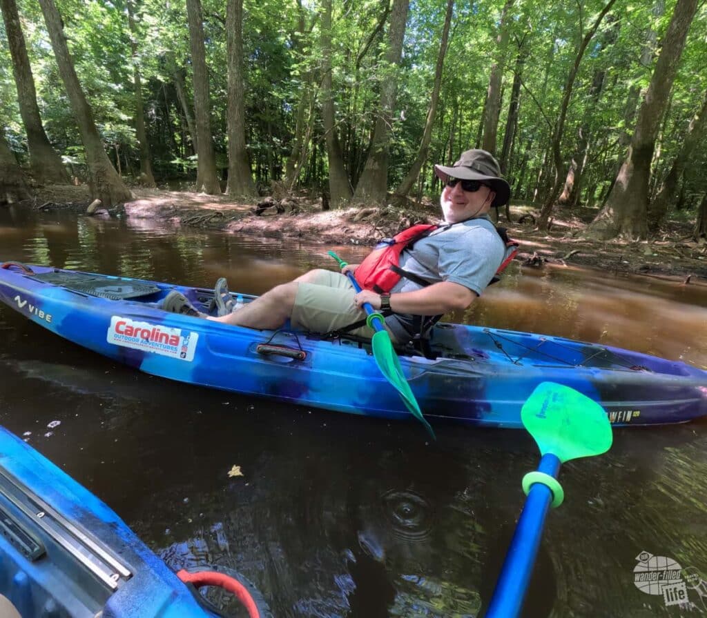 Grant sitting in a kayak on Cedar Creek in Congaree National Park. He is holding his paddle in his hand.