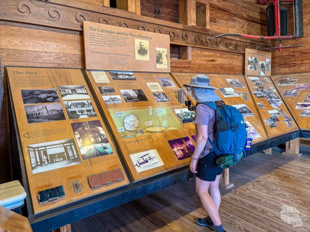 A woman wearing a backpack looking at a museum exhibit.
