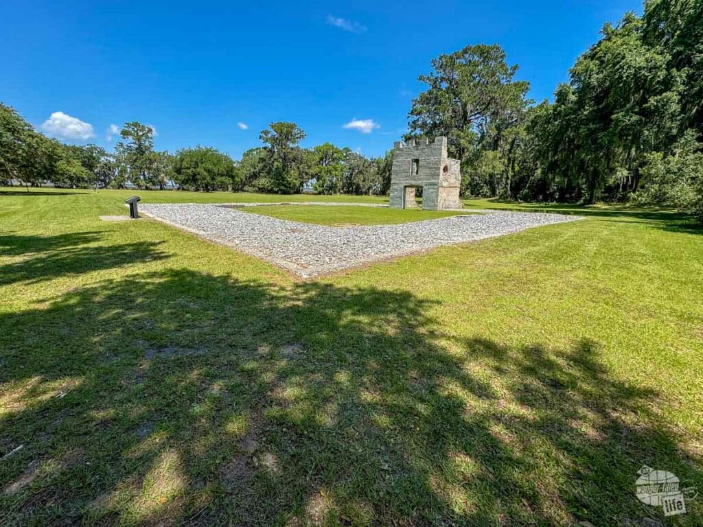 A stone foundation with a fireplace in a field.