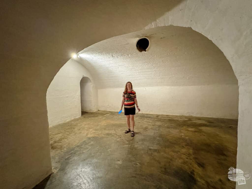 A woman standing inside a vast, open storage room with a arched ceiling.