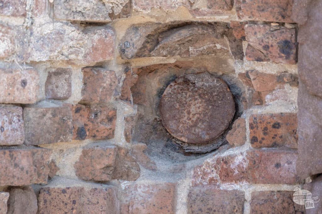 A large, round projectile embedded in a brick wall.