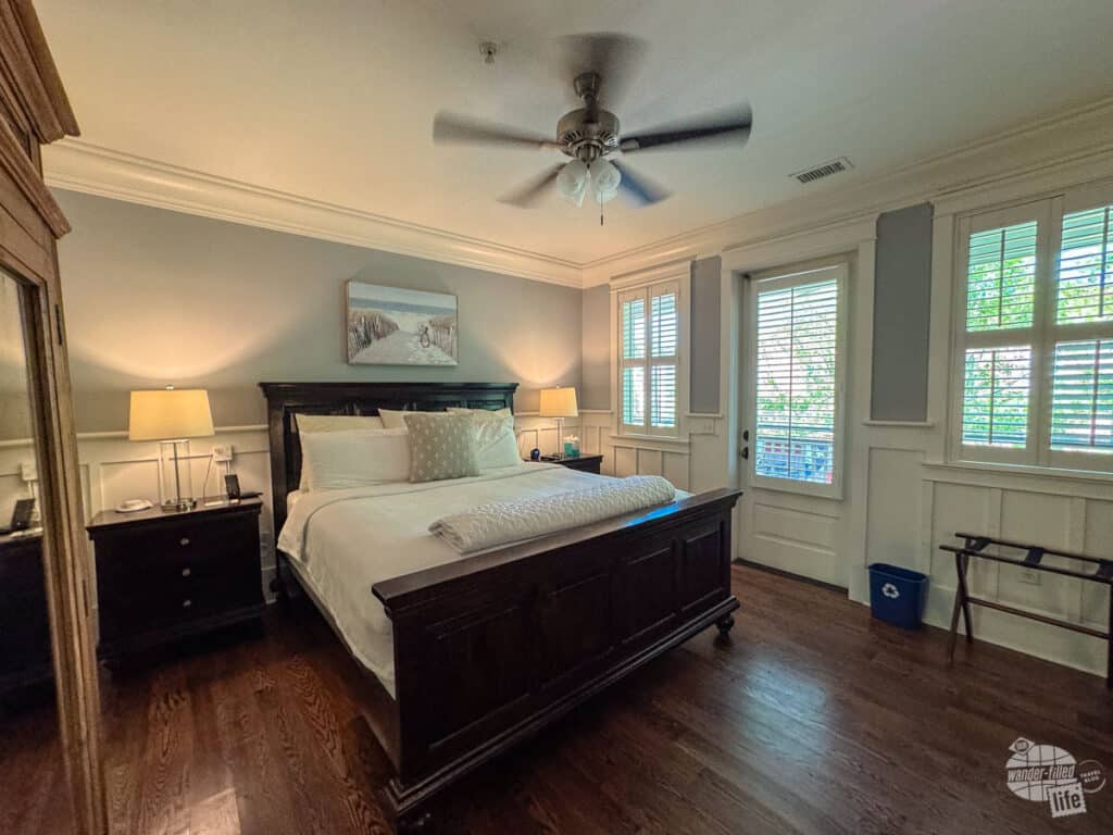 A large king bed with nice hardwood floors and a celing fan above.